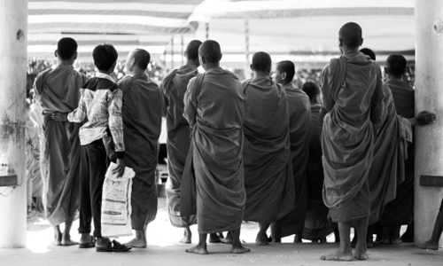 Young monks wait to join their peers. Monks receive offerings of food and money from devout Buddhists to receive their blessing and to help the spirits of their ancestors that died at the Killing Fields. Photo by Danielle Fultz.