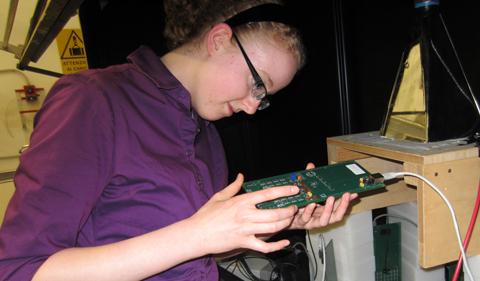 Natalie Klco examining an electronics board that controls the LED pulsing for the calibration setup in Genoa, Italy