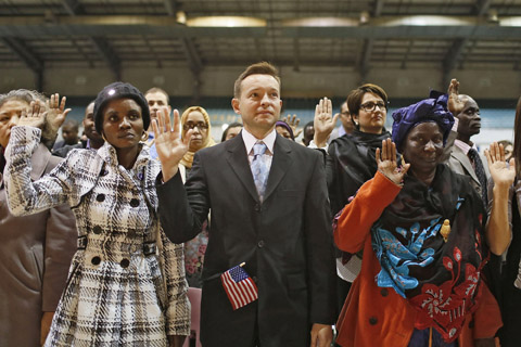 Eric Letourneaux, center, 42, takes the citizenship oath with about 75 others before the Columbus International Festival. Photo by Kristen Zeis, Columbus Dispatch