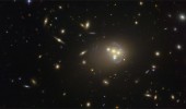This image from the NASA/ESA Hubble Space Telescope shows the rich galaxy cluster Abell 3827. The strange blue structures surrounding the central galaxies are gravitationally lensed views of a much more distant galaxy behind the cluster. Observations of the central four merging galaxies have provided hints that the dark matter around one of the galaxies is not moving with the galaxy itself, possibly implying dark matter-dark matter interactions of an unknown nature are occurring. Credit:
ESO