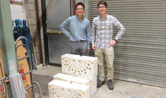 Nuclear physicists Tony Ahn and Zach Meisel stand on the dock at the Edwards Accelerator Lab and behind section of the polyethylene blocks used to slow down neutrons. The holes are where the detectors are placed.