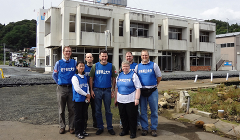 Dr. Christopher Thompson, with (L-R) Dr. Joe Shields, OHIO alums Yuko Kuwahara, and Todd Fouts, Dr. Tom Scanlan, Provost Pam Benoit, and OHIO alum and Chubu University professor Greg King in front of a destroyed fisheries building on the waterfront in Otsuchi, Iwate in September, 2012.