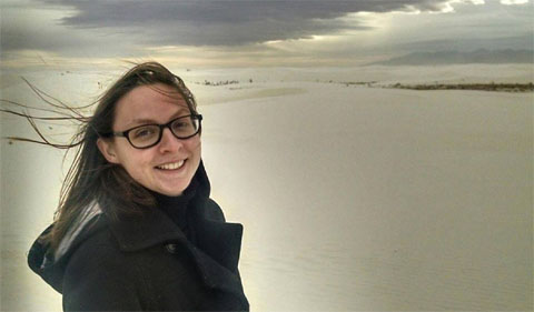 Annalycia Liston-Beck at the White Sands National Monument in New Mexico. She is wearing a coat, the wind is blowing her hair, with the white sands in the background.