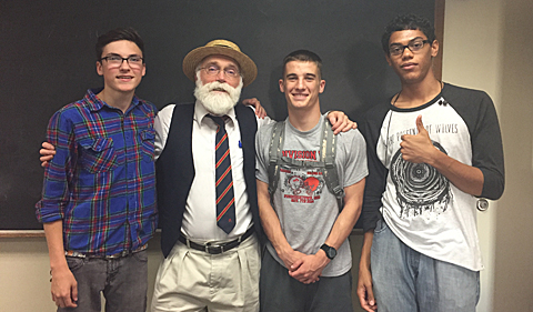 Patrick McGee and students Demetri Wolfe-Maris, Gavin Stalnaker, and Zachery Wagner pose in front of a blackboard