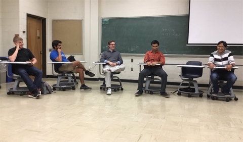 Five Math Department grad students share their experiences working at national summer math camps.  They are seated in an arc at the front of the room.