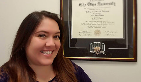 Dana Brown with her framed Ohio University degree on the wall next to her