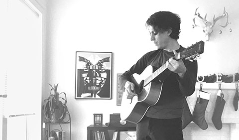Jonathan Norstrom standing in living room playing guitar