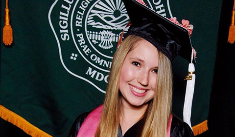 Natalee Bailey in cap and gown in front of Ohio University Banner