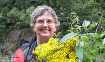 Dr. Vicki Funk, holding yellow flowering plant