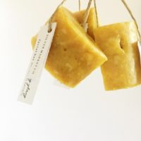 three yellow SM Co. handmade soaps hanging by string with a label