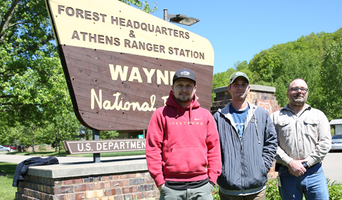 Interns Samuel Heckle and Zachary Matthews, with Wayne member, standing in front of Wayne National Forest sign