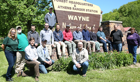 Ohio University interns with faculty and staff from OHIO and the Wayne National Forest, standing as a group in front of the Wayne sign.