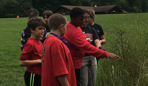 Jen Hastings asks campers to read a thermal gun directed at plants in the prairie. 