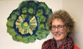 Dr. Theresa Moran, Food Studies Theme Director, stands next to student art depicting a garden where students grow produce now offered in campus venues.
