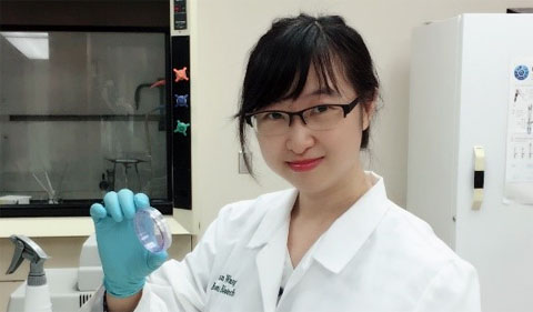 Xuan Wang, holding up sample in her white lab coat