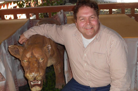 Michael Kukral in Kenya, posing here with a carving of a lion.
