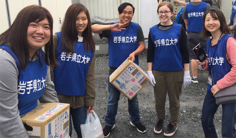 OHIO students and future OPIE students deliver water to Tsunami victims, shown here in blue vests with boxes of water.