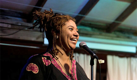 Dr. Bianca Spriggs, performing at a microphone