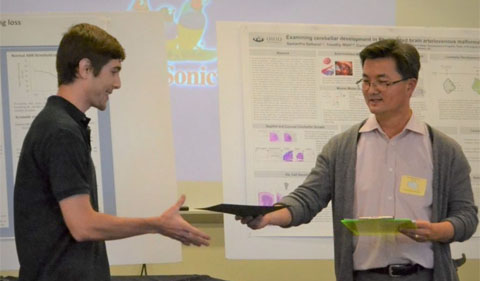 Biological Sciences professor Daewoo Lee presents Brockway with his award at Neuroscience Research Day.