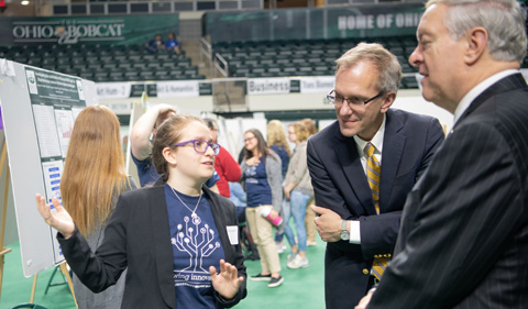 Madeline Sudnick (Left) presents her research to Vice President for Research; and Dean of the Graduate College Joe Shields (Center) and President Nellis at the Student Expo. Photo by Ben Siegel 
