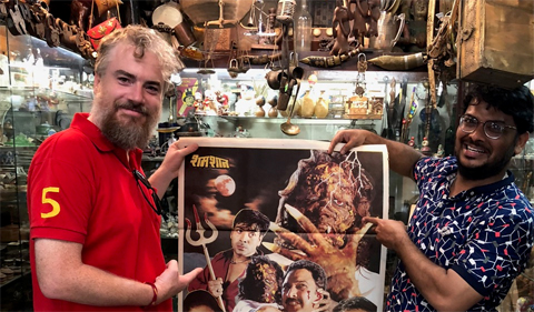 Dr. Brian Collins holds a horror film poster from India.