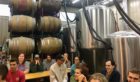 Students sit at Little Fish Brewery and listen to owner and head brewer, Sean White, explain the process of opening a brewery and its role as a community space.