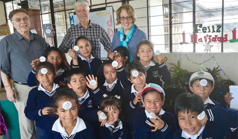 From left: Dr. David Bell (Linguistics), Dr. Art Trese (Environmental & Plant Biology), and Dr. Theresa Moran (Food Studies) and the schoolchildren of Yunguilla with their Food Studies stickers.