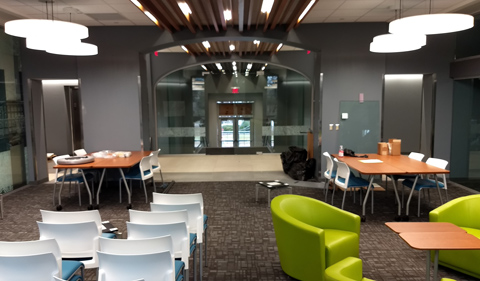 New student collaborative workspace in Ellis Hall, with lighed ceiling beams and colorful groupings of chairs.