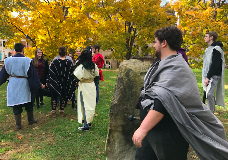 Costumed students stand near boulder