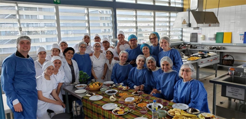 Students in the kitchen in Ecuador, donning blue gowns and hair covers