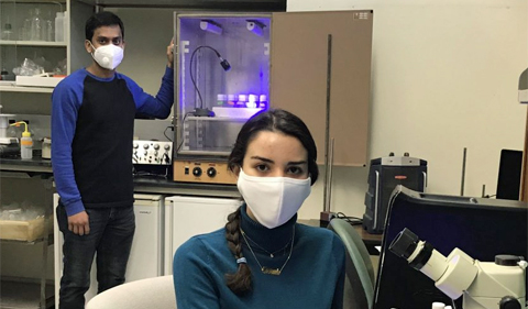 Graduate students Sarah Baitamouni (seated) and Reaz Uddin (standing) demonstrating setups in lab used for light activated experiments.