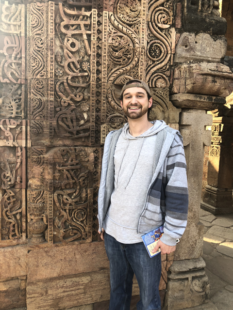 Andrew Howard at the Qutb Minar complex in Delhi, which contains one of the oldest mosques in India and has Arabic writing behind him in the same script used to write Urdu (and Persian). The mosque was built using stones from Hindu and Jain temples, which is evidenced by the Hindu deities and Jain motifs still visible on many of the stones within the complex.