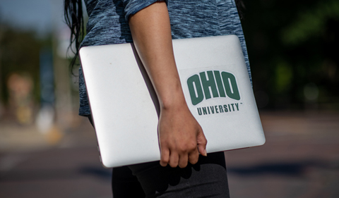 Student walking with laptop and Ohio University sticker