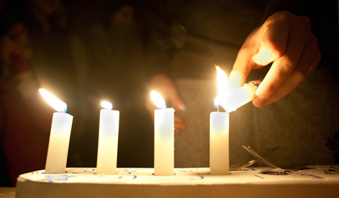 Joey Rosen lights a menorah during a cermony held tuesday on the porch of the Alpha Epsilon Pi fraternity in celbration of the fourth night of Hanukkah. There ceremony was attended by jewish members of Alpha Epsilon Pi, Sigma Kappa sorority and Rabbi Danielle Lehaw. Also pictured are Ruthie Leshaw (left), Lauren Devinson (second from left) and Janie Silverman (center). Photo by: Ross Brinkerhoff.
